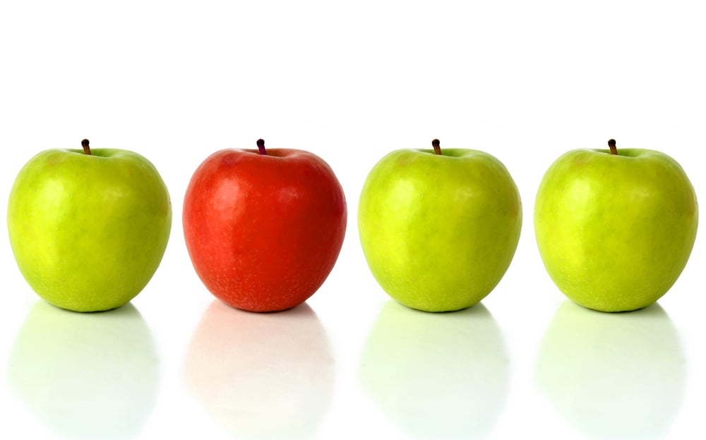 green apple with the red one standing out from the crowd - over a white background with reflection-1